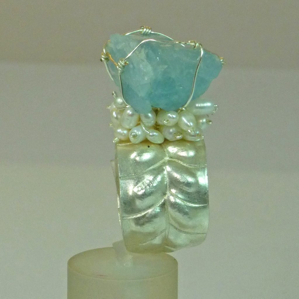 Bague sur mesure en argent ornée d'une pierre bleuâtre et de perles blanches.