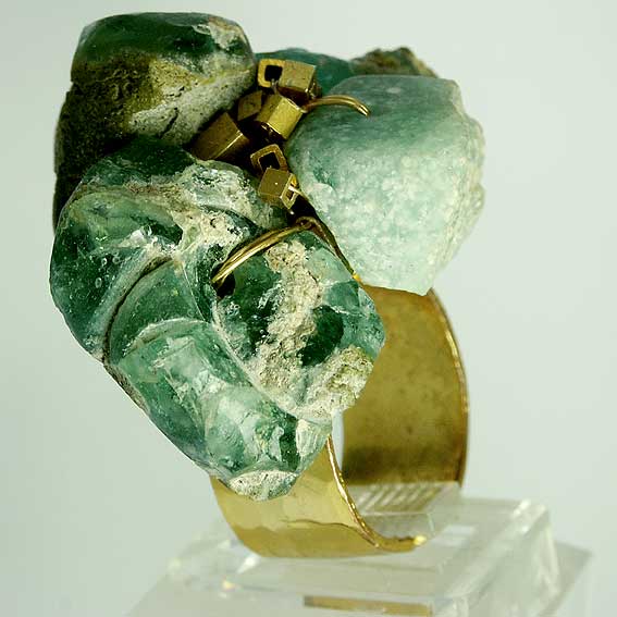 Bague avec des pierres vertes et une monture dorée.