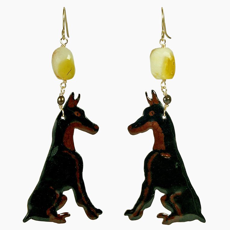 A pair of earrings designed with black and brown Doberman dog silhouettes, featuring a decorative yellow bead at the top.