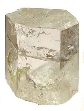 Un cristal de béryl incolore présentant une croissance hexagonale, avec des inclusions visibles et une forme robuste.