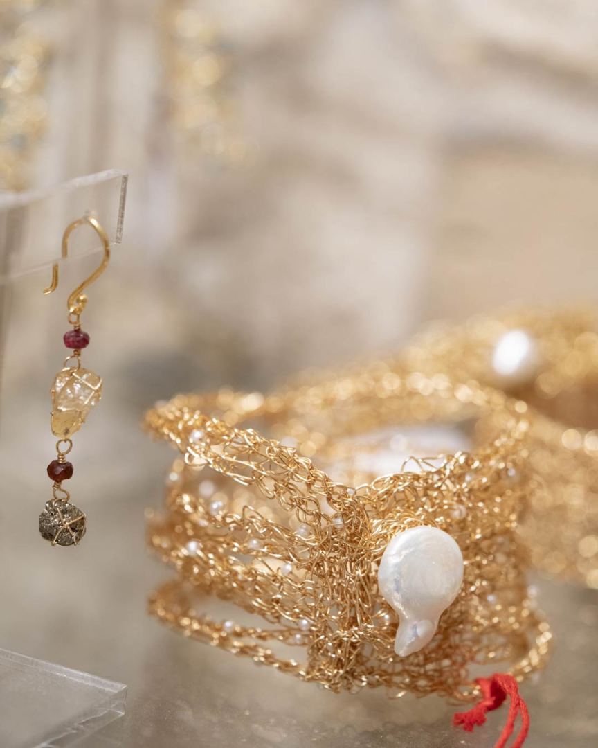 Boucles d'oreilles en or avec pendentif et bracelets dorés ornés de perles.