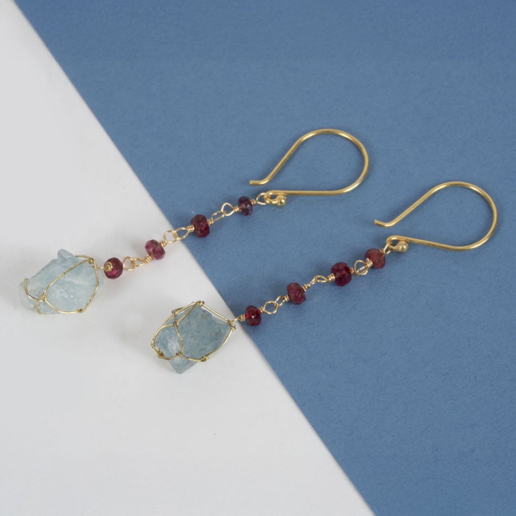 Boucles d'oreilles en or avec des pierres brutes bleues et des perles rouges.